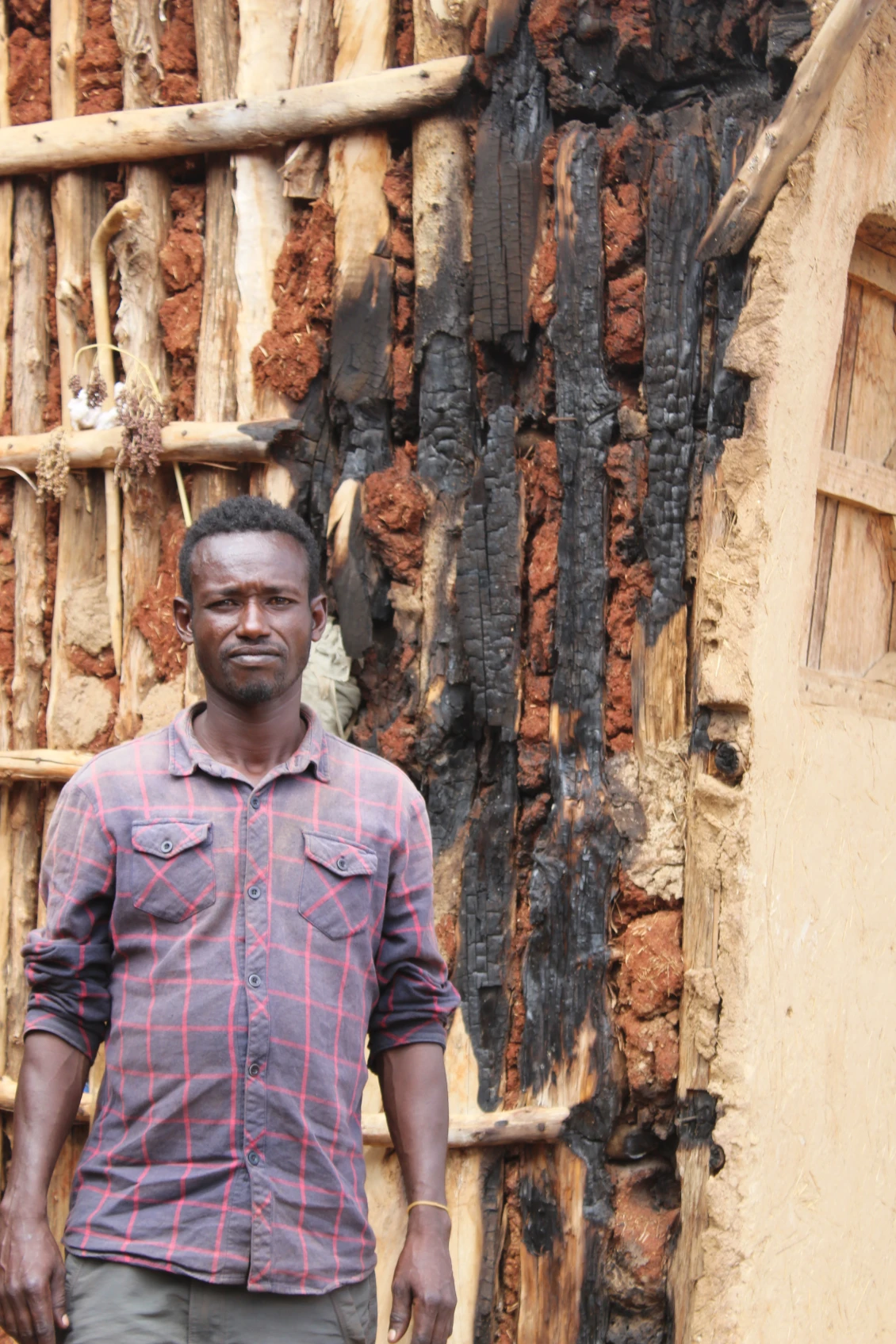 Abera next to his destroyed house.
