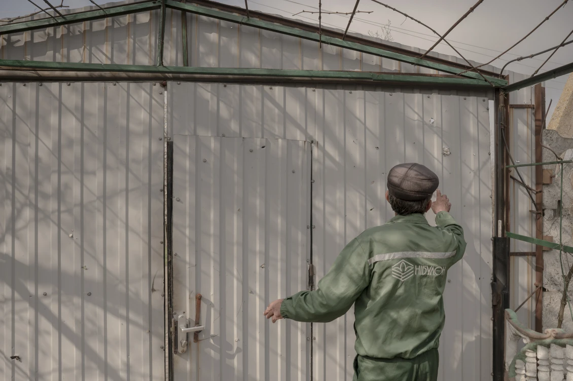 Oleksandr shows a shrapnel-damaged building in his yard