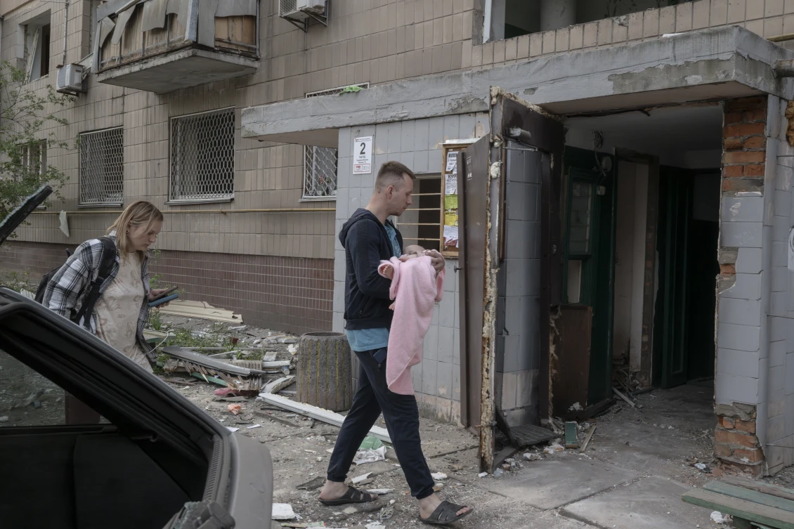 Carrying their baby, a couple enters a damaged building in Kyiv. 
