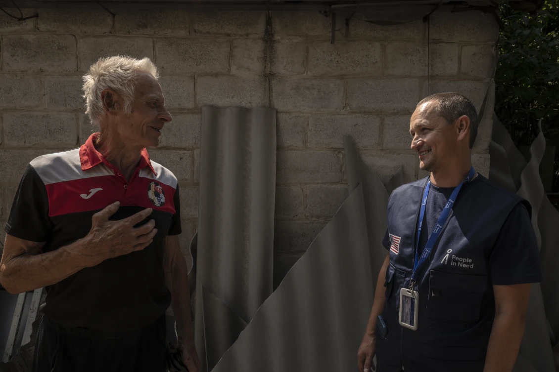 Serhii talks with the owner of a damaged house during a visit to an affected community